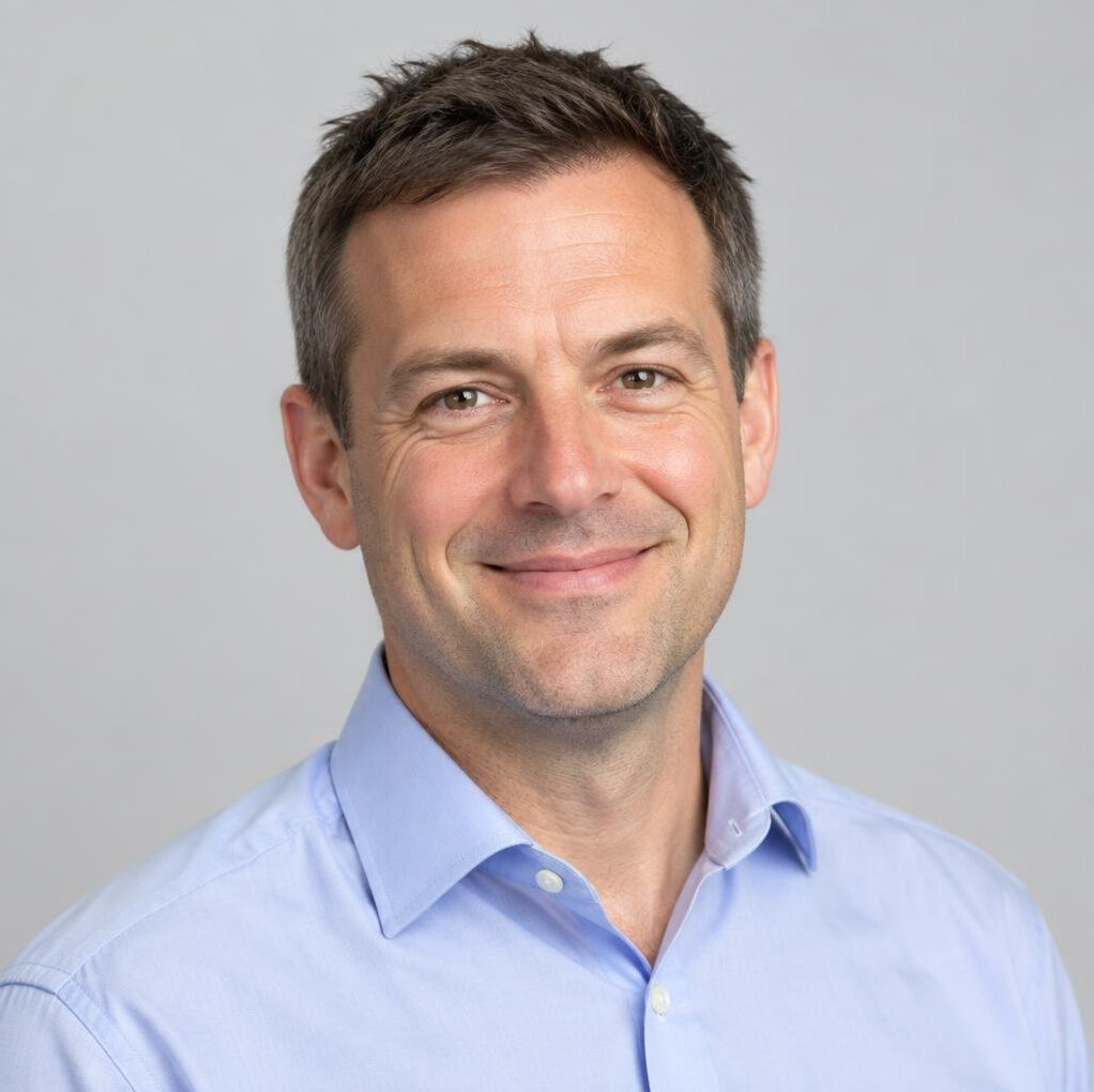 Studio headshot of a British man, a news editor, smiling
